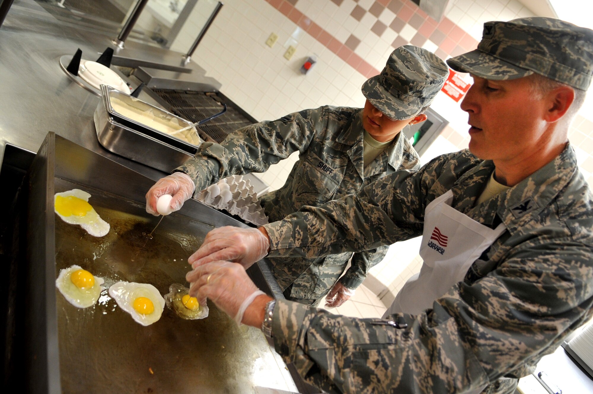Col. Paul Bauman, 319th Air Base Wing commander, cooks eggs with Airman 1st Class Brittney Shuff, 319th Force Support Squadron, at the Airey Dining Facility on Grand Forks Air Force Base, N.D., on Aug. 9, 2013. Bauman and Chief Master Sgt. David Duncan, 319th Air Base Wing command chief, spent the morning working day-to-day jobs with members of the 319th Force Support Squadron. (U.S. Air Force photo/Staff Sgt. Amanda Grabiec)