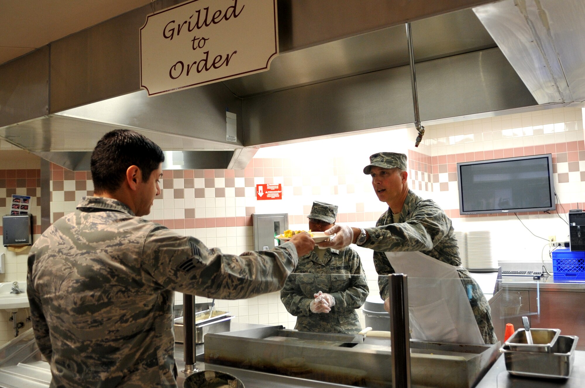 Col. Paul Bauman, 319th Air Base Wing commander, serves breakfast to Senior Airman Anthony Hernandez, 69th Maintenance Squadron, at the Airey Dining Facility on Grand Forks Air Force Base, N.D., on Aug. 9, 2013. Bauman and Chief Master Sgt. David Duncan, 319th Air Base Wing command chief, spent the morning working day-to-day jobs with members of the 319th Force Support Squadron. (U.S. Air Force photo/Staff Sgt. Amanda Grabiec)