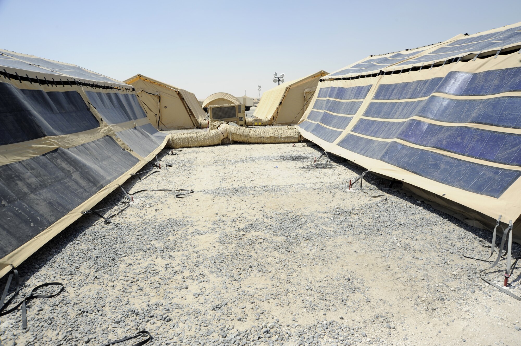Two tents with photovoltaic panels on the flys are awaiting final touches with sensors for testing here, Aug. 12, 2013. Since the tents already use flys as shade, researchers placed the photovoltaic panels on some of the flys to harness the sun's energy and actually generate energy which can be channeled back into the power grid. The panels can generate about a megawatt of power for a full base. (U.S. Air Force photo by Master Sgt. Christopher A. Campbell)