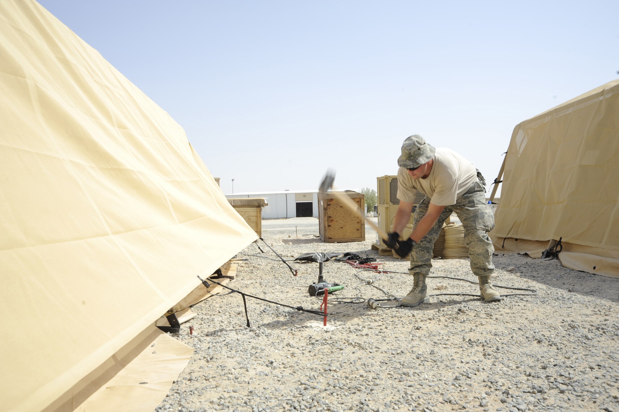 Staff Sgt. Kevin Taylor, 386th Expeditionary Civil Engineer Squadron, structures flight, swings a sledge hammer here, Aug. 6, 2013. Taylor is hammering in stakes to secure a tent. He is working together with members of the Air Force Civil Engineer Center testing new energy-efficient technologies to reduce the amount of energy for future operations. Taylor is deployed out of the 110th Airlift Wing, Battle Creek, Mich., Air National Guard unit. (U.S. Air Force photo by Master Sgt. Christopher A. Campbell)