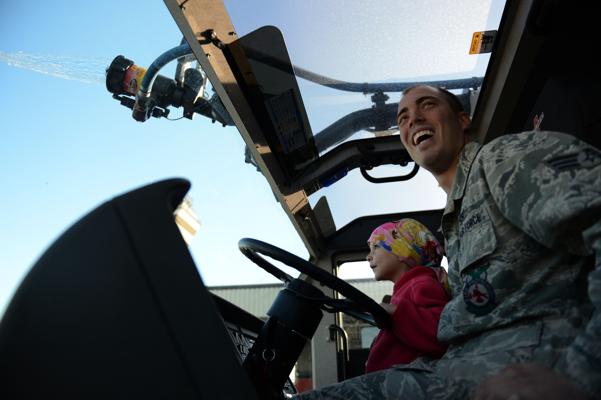 SPANGDAHLEM AIR BASE, Germany – U.S. Air Force Senior Airman Steven Douglass, 52nd Civil Engineer Squadron fire protection technician from Valley City, Ohio, shows Sarah Pittman, 4, how to operate the water cannon aboard a fire truck Aug. 16, 2013. Sarah was diagnosed with leukemia in December 2010. Although she no longer needs IV chemotherapy, she regularly receives checkups and medication at the Mutterhaus der Borrormaerinnen in Trier. (U.S. Air Force photo by Airman 1st Class Gustavo Castillo/Released)