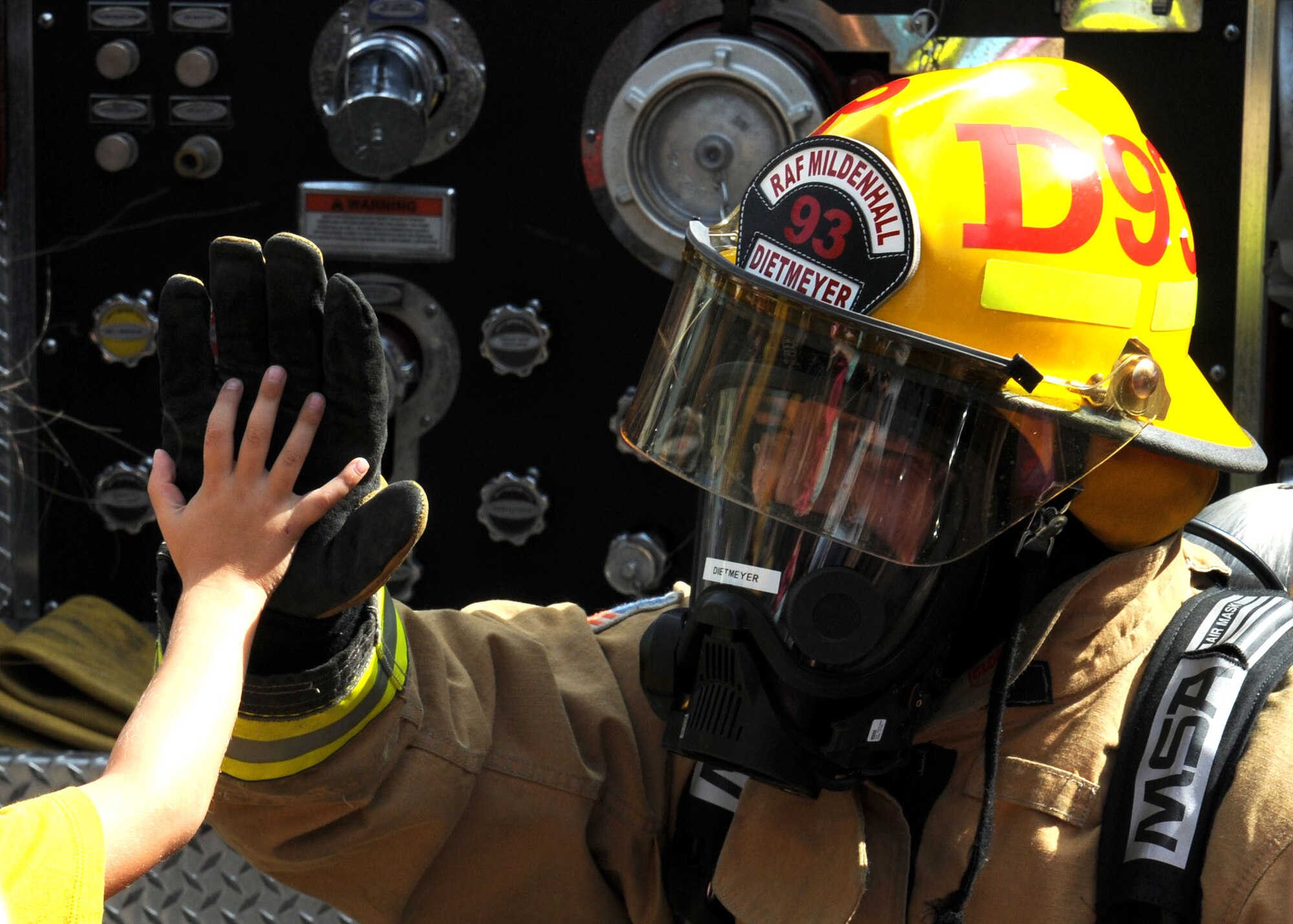 U.S. Air Force Airman 1st Class Jacob Dietmeyer, 100th Civil Engineer Squadron Fire Department firefighter from Gurnee, Ill., high-fives a Team Mildenhall child following a book-reading session Aug. 21, 2013, at the library on RAF Mildenhall, England. The firefighters taught the children firefighters are not to be feared. The firefighters also hoped that by seeing them as real people, in the event of an emergency children would not panic and would follow firefighters’ instructions to safety. (U.S. Air Force photo by Gina Randall/Released)