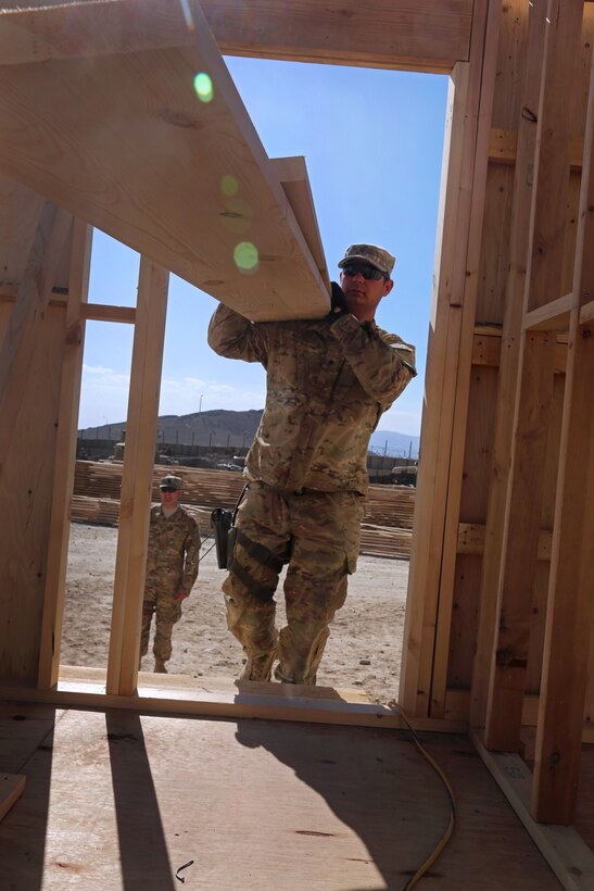 U.S. Army Spc. Samuel McCoy carries pieces of wood into the new tactical operation center on Forward Operating Base Lightning in Paktiya province, Afghanistan, Aug. 20, 2013. McCoy is assigned to the 149th Vertical Construction Company.