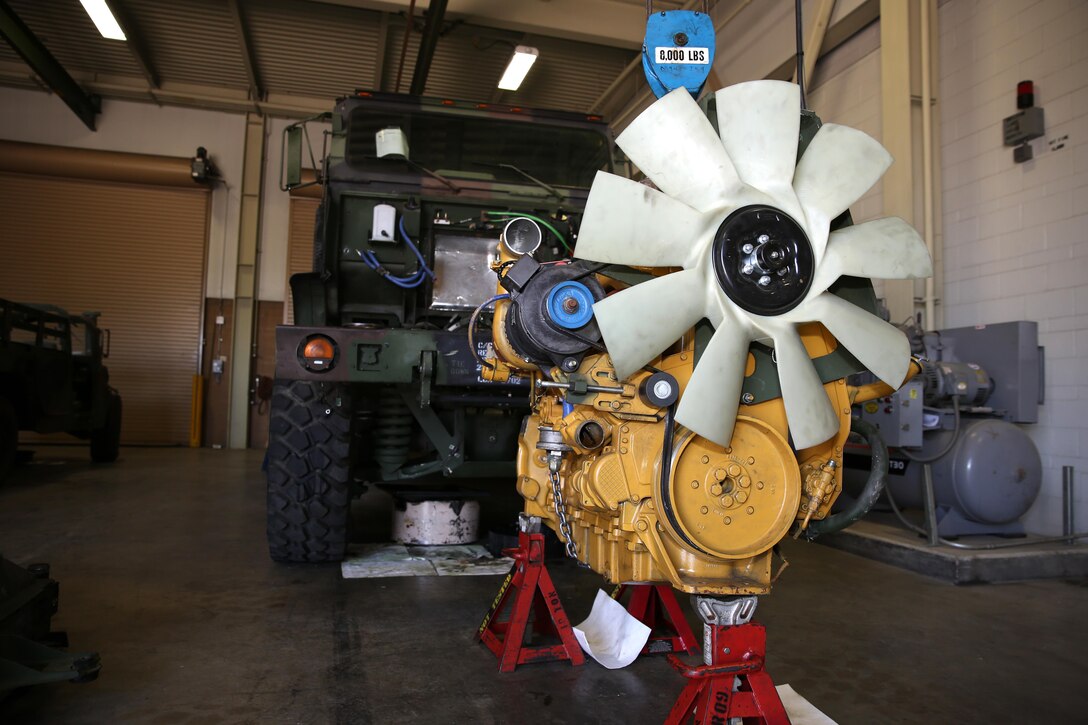 The engine of a Medium Tactical Vehicle Replacement sits on stands and is held in place by a pulley system in the Combat Logistics Company 11 maintenance bay after being pulled out of the vehicle for repairs aboard Marine Corps Air Station Miramar, Calif., Aug. 13. This engine weighs more than can be lifted by normal means and requires a forklift in order to remove it from the vehicle.
