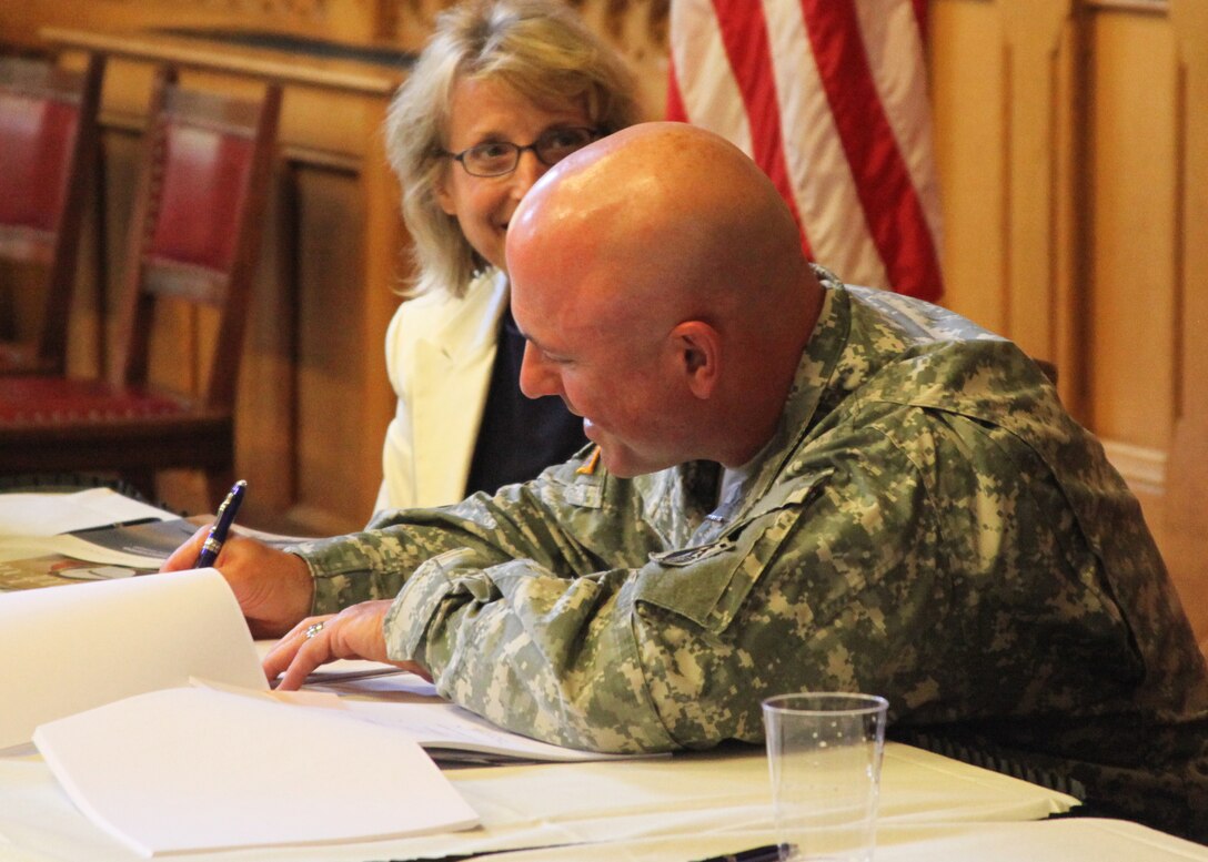 Col. Charles Samaris, commander and district engineer, U.S. Army Corps of Engineers, New England District, signs the official National Audubon Society, Inc. -- Connecticut Chapter In-Lieu Fee agreement that provides an alternative form of compensatory mitigation to those applicants seeking permits from the Army Corps of Engineers for work in Connecticut, while Barbara Newman, a regulator with the Corps watches.