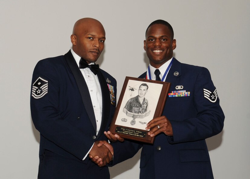 Staff Sgt. Courtney Johns, 2nd Operation Support Squadron, receives the Commandant's Plaque from Master Sgt. Donnel Graham, 2nd Civil Engineer Squadron, during the Airman Leadership School Class 13-5 Graduation on Barksdale Air Force Base, La., June 21, 2013. (U.S. Air Force photo)