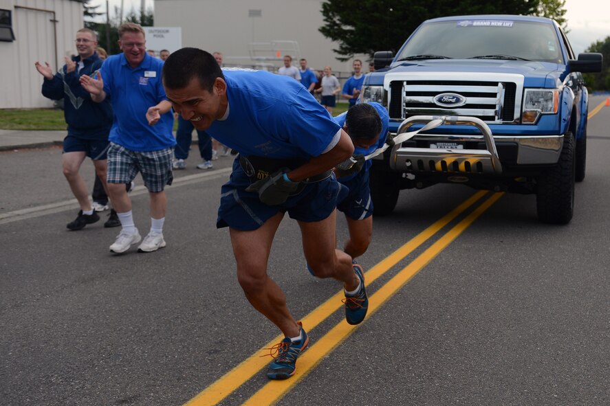 Andy Oczkewicz (left), USO center manager for the Puget Sound area, cheers on Col. David Kumashiro, 62nd Airlift Wing commander, and Capt. Jonathan Dedic (front), 62nd Operations Support Sqaudron, as they pull a truck during the Team McChord Sports Day Aug. 23, 2013 at Joint Base Lewis-McChord, Wash. Honorary commanders and civic leaders took part in Sports Day 2013 and learned how Airmen worked together for an ultimate goal. (U.S. Air Force photo/Airman 1st Class Jacob Jimenez)