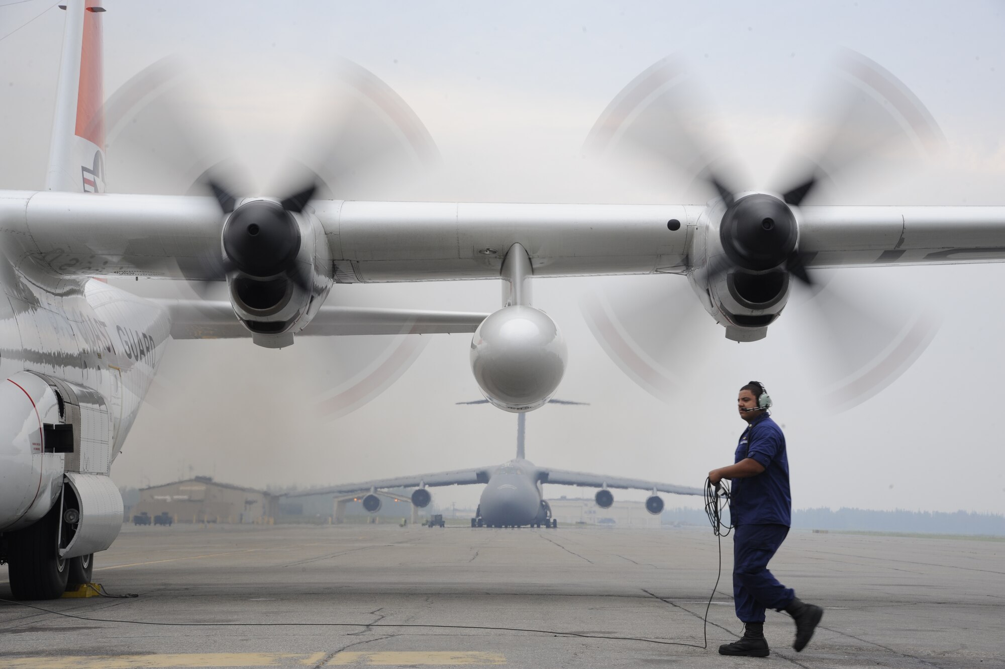 An aviation maintenance technician coils a power cord as pilots perform a low-speed ground idle engine run to test repairs to an engine Aug. 15, 2013, Eielson Air Force Base, Alaska. The U.S. Coast Guard HC-130H Hercules aircrew visited Eielson recently as part of a flying mission to and above the Arctic Circle. Coast Guard aircrews often assist studies and research projects of various organizations, such as the National Oceanic and Atmospheric Administration and the University of Washington, in collecting data. (U.S. Air Force photo by Airman 1st Class Peter Reft/Released) 

