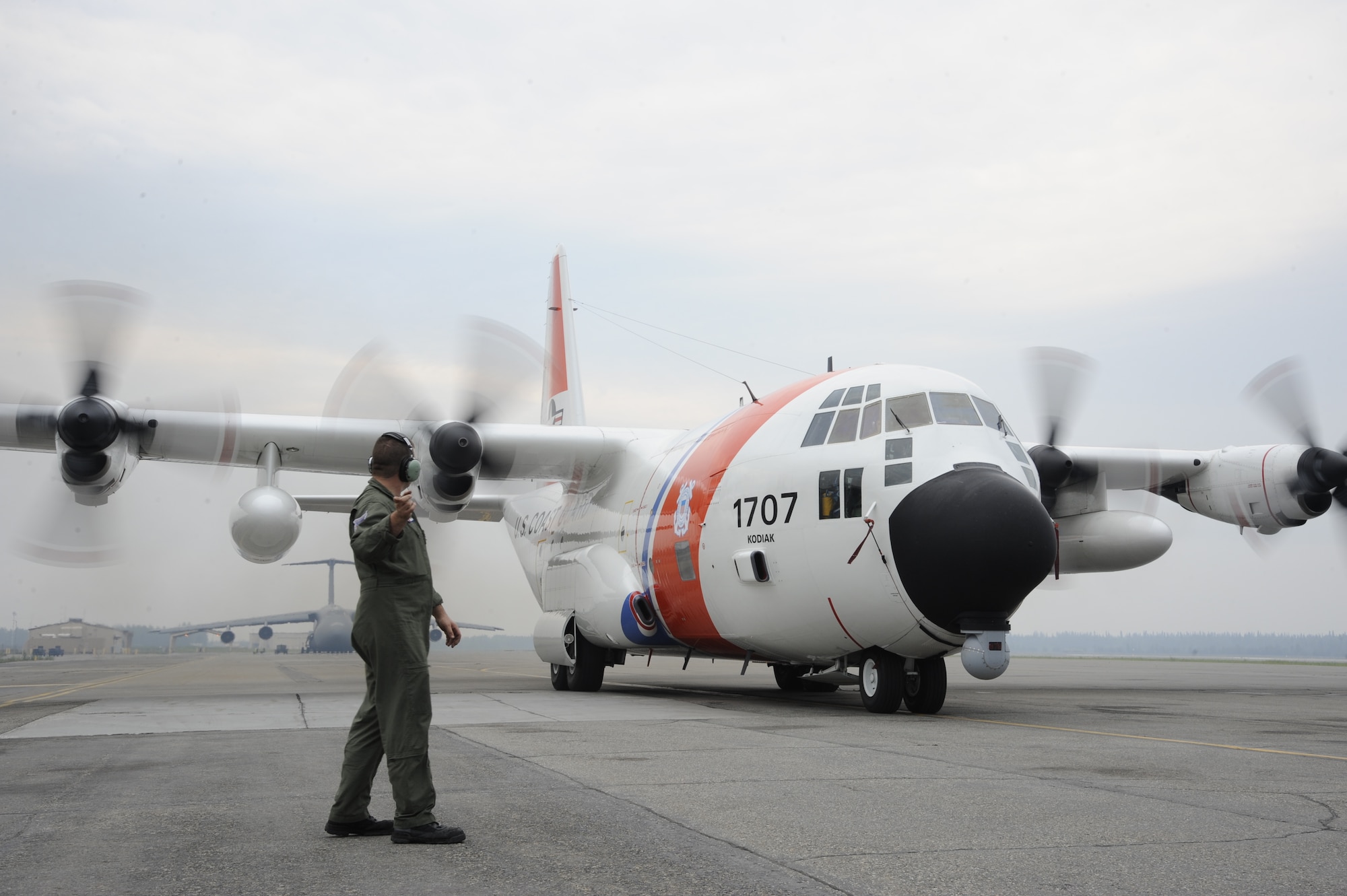 An aviation maintenance technician signals to pilots as they perform a low-speed ground idle engine run to test repairs to an engine Aug. 15, 2013, Eielson Air Force Base, Alaska. The U.S. Coast Guard HC-130H Hercules aircrew visited Eielson recently as part of a flying mission to and above the Arctic Circle. Eielson provided support to the visitors during the repairs so they could complete their mission. (U.S. Air Force photo by Airman 1st Class Peter Reft/Released) 