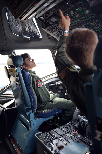 Capt. Mike Knapp, 4th Airlift Squadron awards and decorations officer, shows Pilot for a Day recipient, Christian Ball what some of the buttons do on the flight deck of a C-17 Globemaster III aircraft Aug. 22, 2013 at Joint Base Lewis-McChord, Wash. This was the first military aircraft Christian had ever sat in. (U.S. Air Force photo/Staff Sgt. Jason Truskowski)