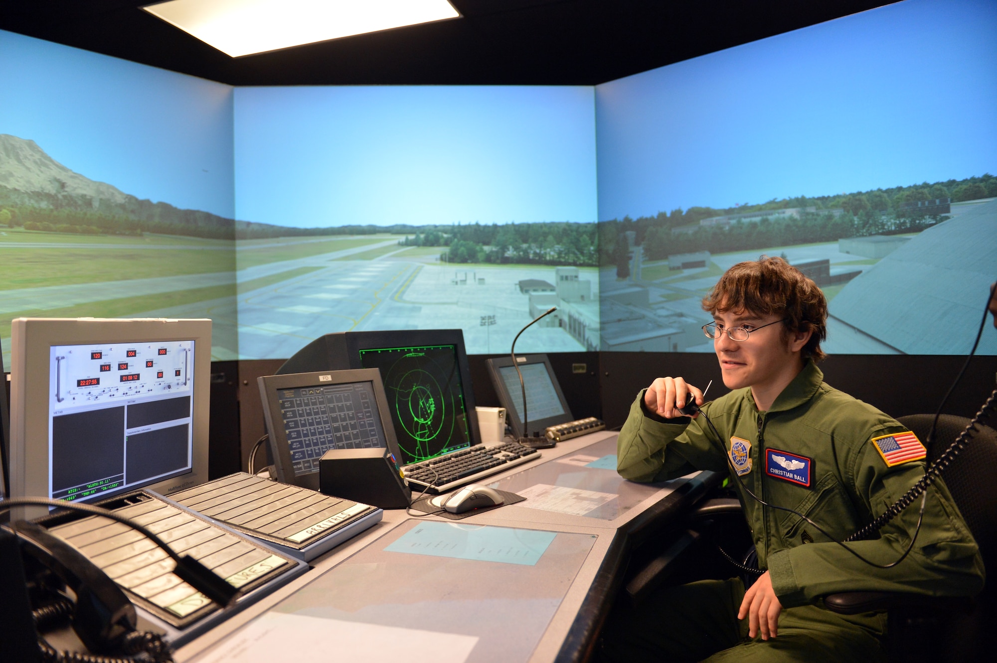 Talking into the microphone of a control tower simulator, Christian Ball, Pilot for a Day recipient, instructs a C-17 Globemaster III aircraft to land Aug. 22, 2013 at Joint Base Lewis-McChord, Wash. Simulator operators added a B-2 Spirit Stealth Bomber and paratroopers into the scenario to put a unique spin on the morning. (U.S. Air Force photo/Staff Sgt. Jason Truskowski)