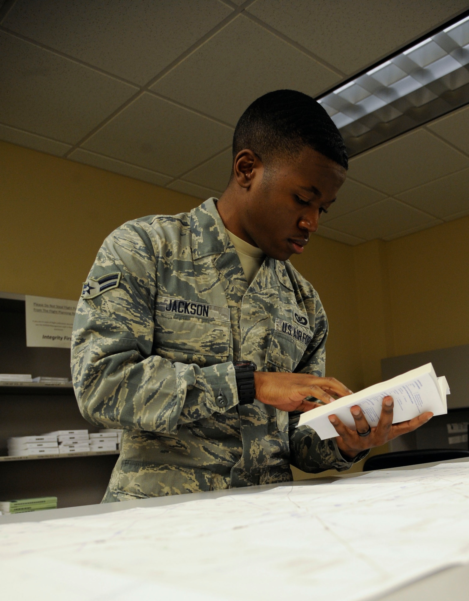 Airman 1st Class Marcus Jackson, 2nd Operations Support Squadron airfield management apprentice, looks over flight maps and a flight information handbook prior to inspecting the flightline on Barksdale Air Force Base, La., Aug. 23, 2013. The map and handbook are used to find an aircraft's route and gain information and access to bases along the route. (U.S. Air Force photo/Airman 1st Class Andrew Moua)