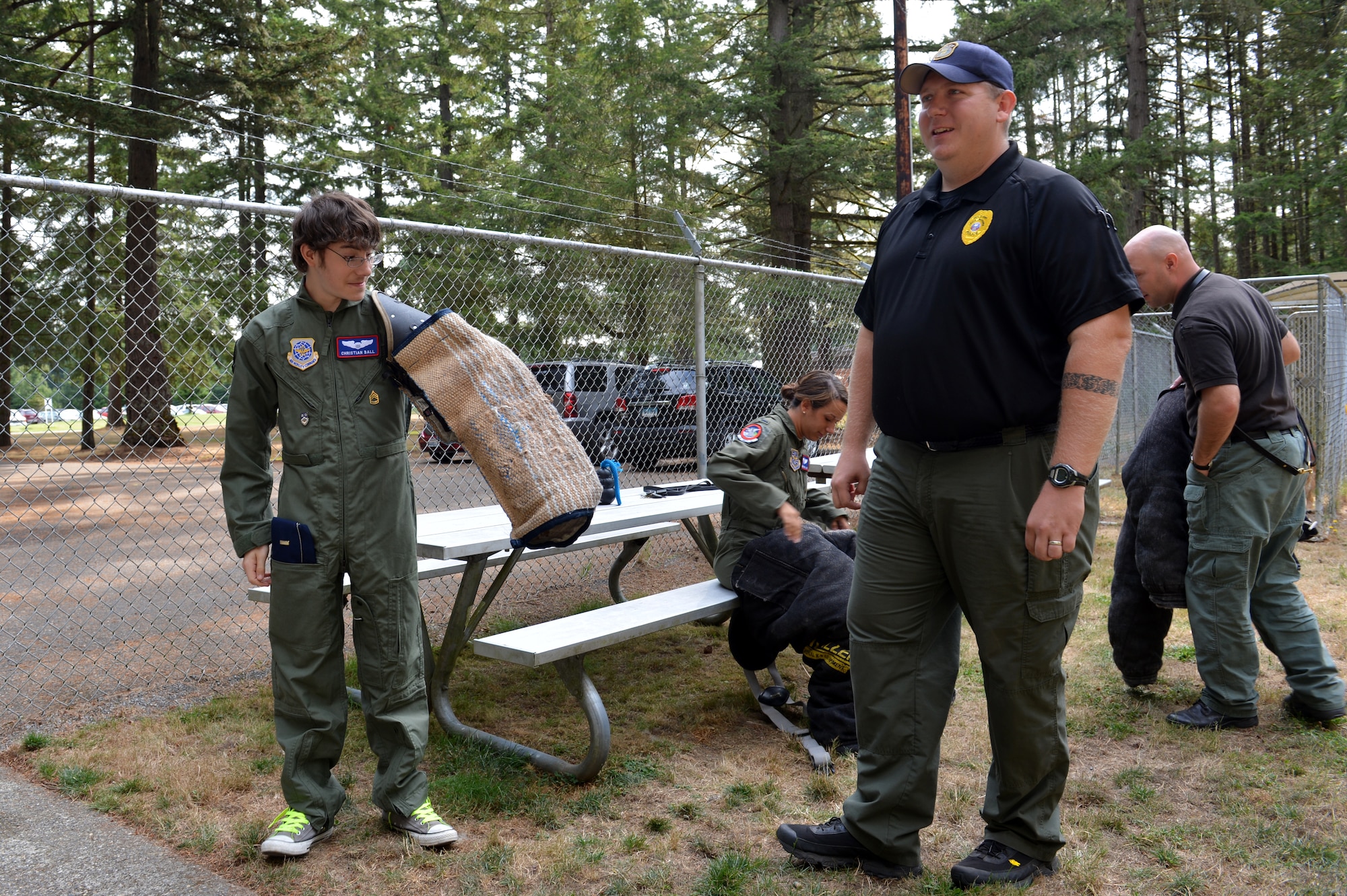 Department of the Army police officers show Christian Ball, Pilot for a Day recipient and Lt. Amanda Robillard, 4th Airlift Squadron co-pilot, the different suits used to train the police dogs Aug. 22, 2013 at Joint Base Lewis-McChord, Wash. Robillard was one of the Airmen who helped plan Christians day at McChord Field. (U.S. Air Force photo/Staff Sgt. Jason Truskowski)