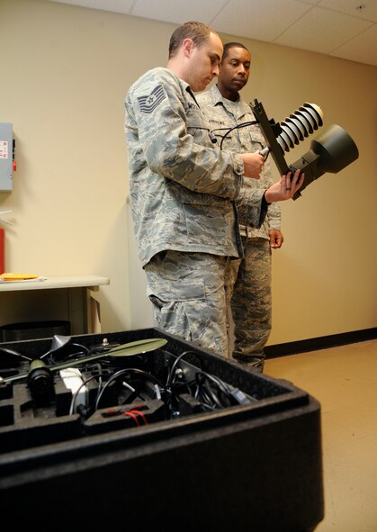 Tech. Sgts. Larry Woodson and Eric Andrews, 2nd Operations Support Squadron weather technicians, inspect a precipitation gauge on Barksdale Air Force Base, La., Aug. 22, 2013. The gauge is a component of a device known as the TMQ-53, which is used by weather technicians who are preparing to deploy to determine weather conditions when down-range. (U.S. Air Force photo/Airman 1st Class Andrew Moua)