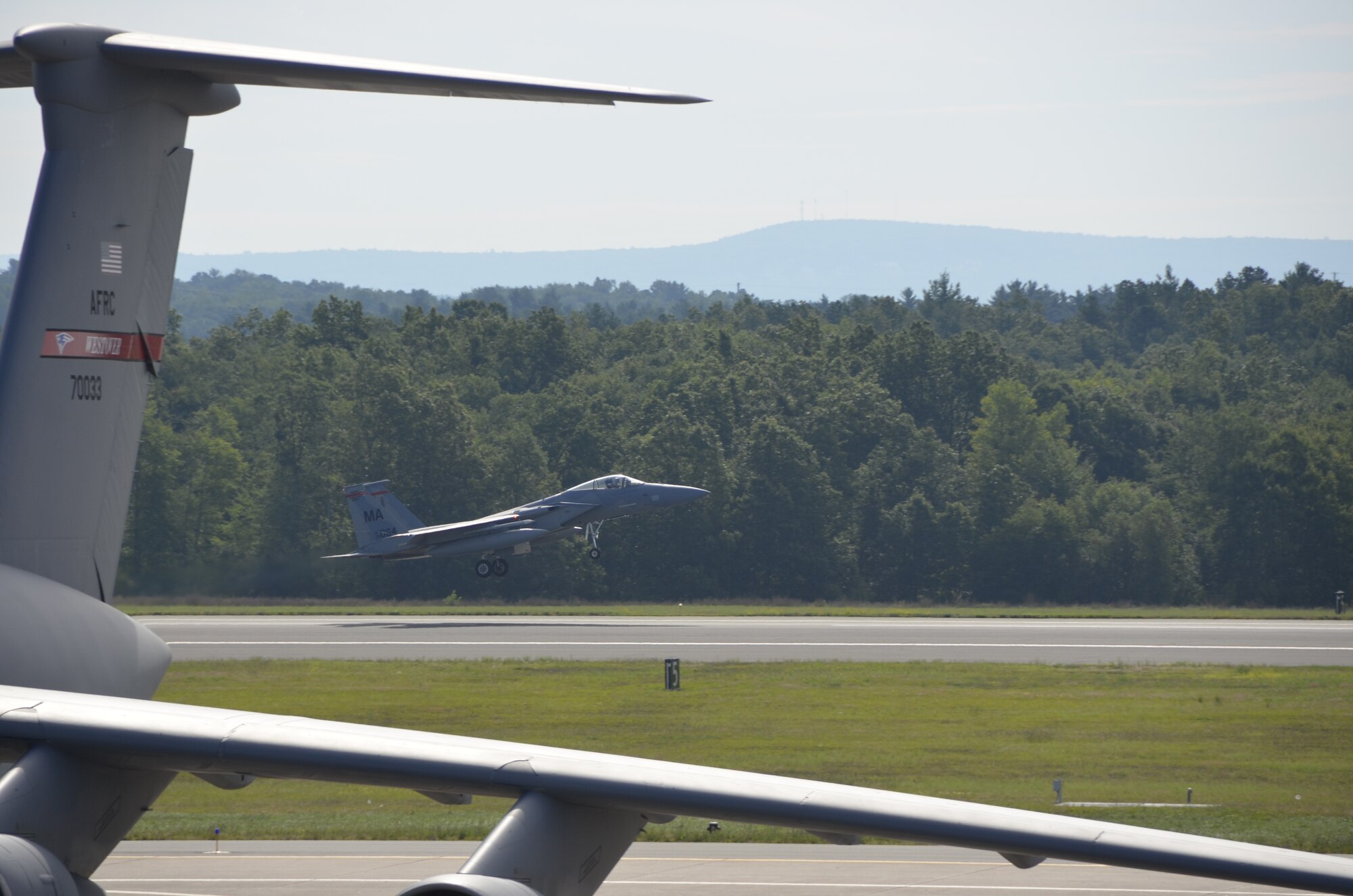 With a C-5 from Air Force Reserve Command's 439th Airlift WIng looming in the foreground, a Massachusetts Air National Guard F-15C Eagle takes off on a training mission from Westover, Aug. 23. The fighters are temporarily assigned to Westover while the runway at Barnes Municipal Airport in Westfield, Mass., undergoes repairs. (US Air Force photo by Master Sgt. Andrew Biscoe)