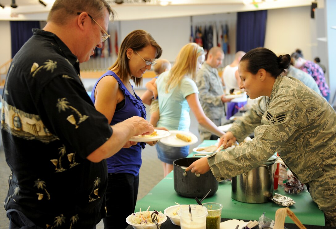 Senior Airman Ashley Avecilla, serves guests a Lebanese dish during the Around the World Cook-off at the Community activity Center on Beale Air Force Base, Calif., Aug. 21, 2013. The free event was hosted by the 9th Force Support Squadron with support from CAC. (U.S. Air Force photo by Staff Sgt. Robert M. Trujillo/Released)