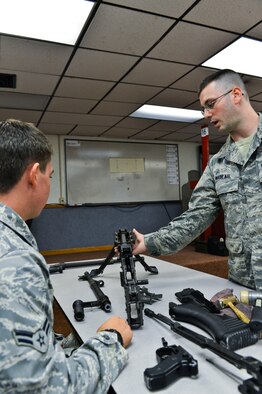 Airman 1st Class Skyler Mills, 56th Security Forces Squadron patrolman, reviews the parts of a weapon with Senior Airman Andrew Nadeau, 56th SFS Combat Arms Training and Munitions instructor, during the classroom portion of M-240B machine gun training Aug. 14 at the Luke Air Force Base CATM building. The Airmen learned about the fundamentals of firing and characteristics of the weapon. (U.S. Air Force photo/Senior Airman David Owsianka)