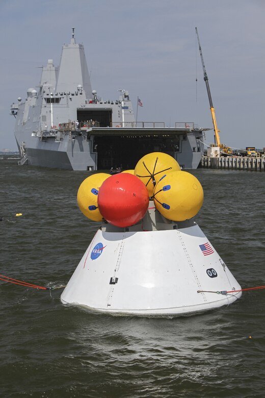 HAMPTON, Va. – An Orion boilerplate test article floats in the water near a U.S. Navy ship during a stationary recovery test Aug. 13 at the Naval Station Norfolk near NASA’s Langley Research Center in Virginia. Members of the 45th Space Wing Operations Group Detachment 3, participated in recovery test operations of NASA’s Orion Multi-Purpose Crew Vehicle aboard the USS Arlington (LPD-24). Detachment 3 personnel served as the liaison between NASA personnel, U.S. Navy Sailors, divers and contractors from across the country. Photo/NASA/Dimitri Gerondidakis
