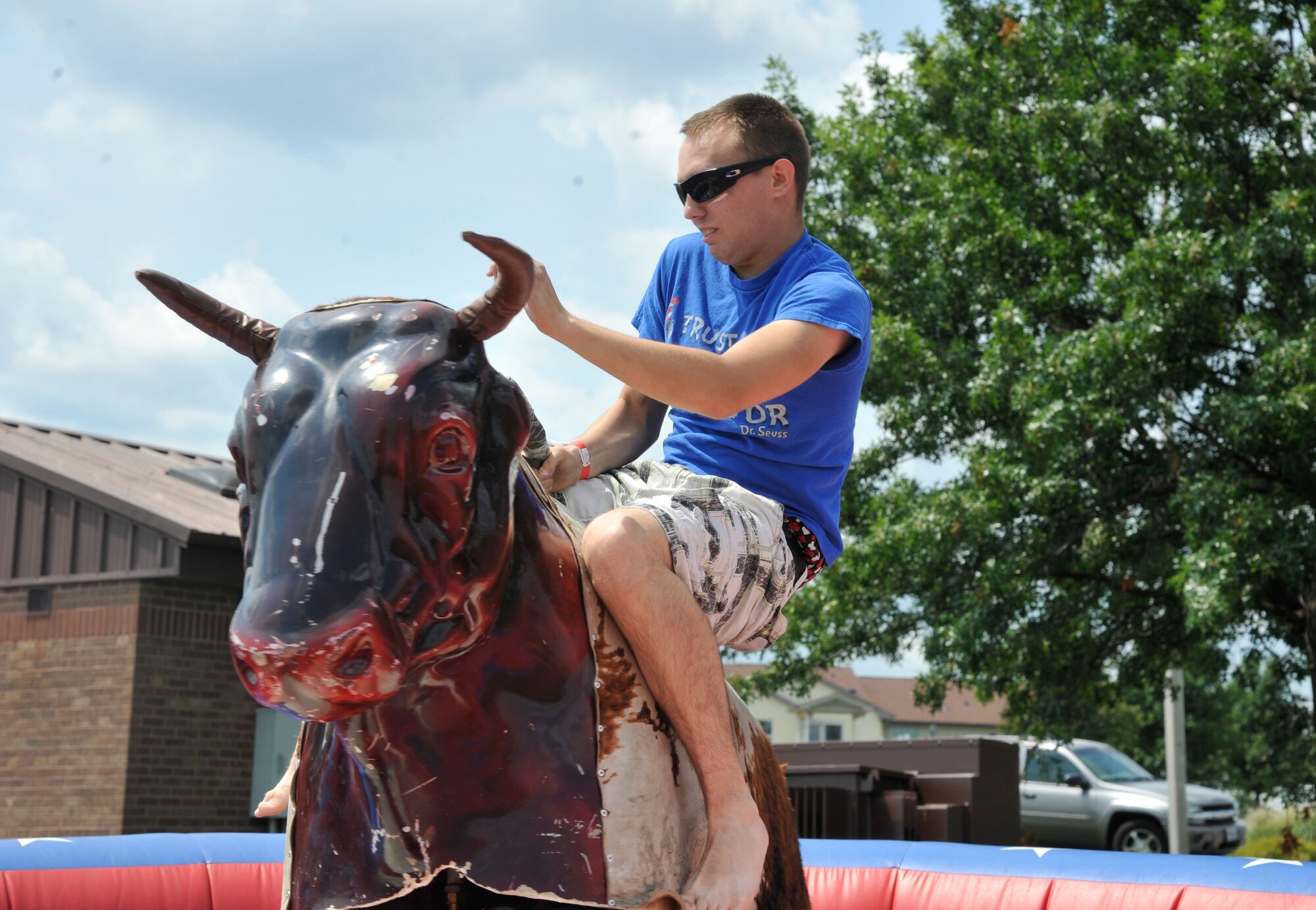 The Airman from the 509th Bomb Wing rides a mechanical bull at Whiteman Air Force Base, Mo., Aug 16, 2013. The Atomic Luau was filled with several events for everyone to enjoy, including live music, bouncy castles, dunk tanks and lots of games. (U.S. Air Force photo by Airman 1st Class Keenan Berry/Released)