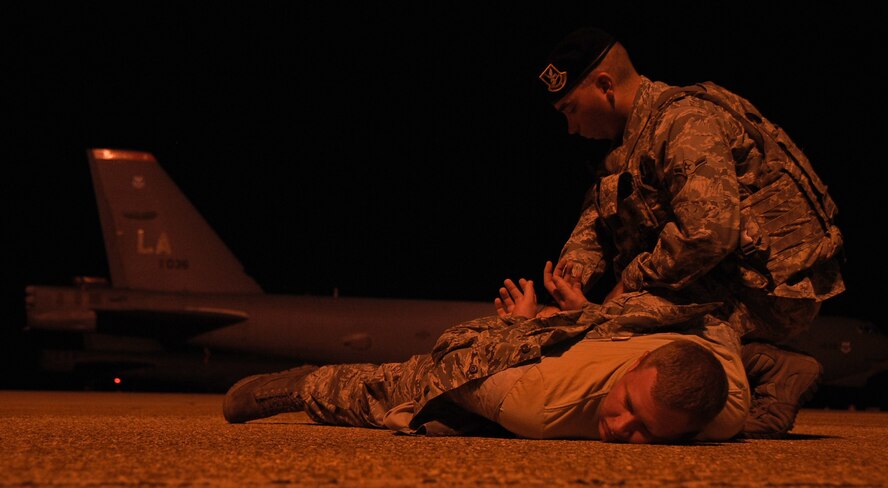Airman Kyle Kauffman inspects Airman 1st Class Thomas Dolan, both from the 2nd Security Forces Squadron for concealed weapons on the flightline at Barksdale Air Force Base, La., Aug. 19, 2013. Working night shift offers a unique training environment due to its limited visibility. This type of shift training improves the Airman's ability to perform in down range environments. (U.S. Air Force photo/Staff Sgt. Jason McCasland 