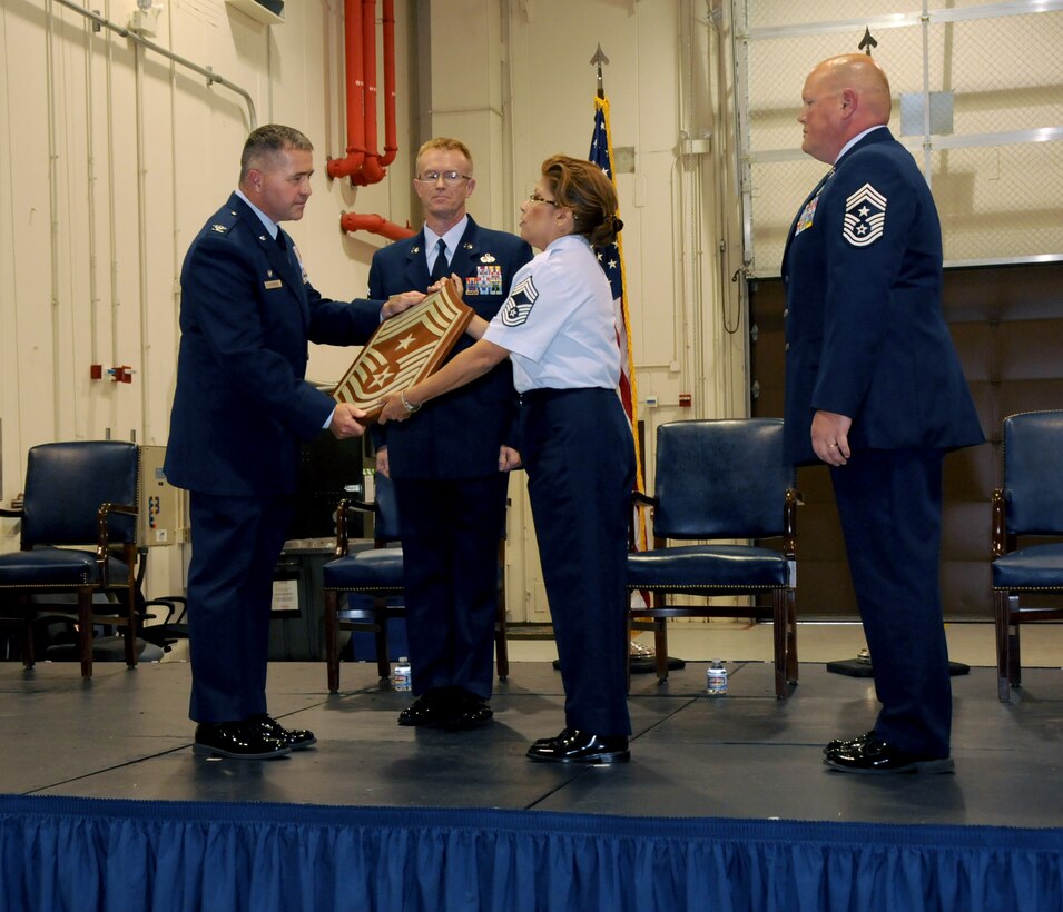 Chief Master Sgt. Regina Stoltzfus, right center, accepts command chief responsibility as Col. John Dickinson, 193rd Special Operations Wing commander passes her a command chief chevron, Aug. 17. Command Chief Stoltzfus is the first female command chief for the 193rd SOW and the sixth chief to hold the position. (U.S. Air National Guard photo by Senior Master. Sgt. David Hawkins/Released)