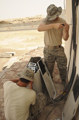 U.S. Air Force Staff Sgt. Matthew Auger, right, and U.S. Air Force Airman 1st Class Anthony Rodriguez, both 380th Expeditionary Civil Engineer Squadron heating, ventillation, and air conditioning journeymen, work to replace an air conditioning system at an undisclosed location in Southwest Asia Aug. 7, 2013. The cooling system being replaced belongs to the commercial power distribution building, which requires a constant cool temperature to keep its systems working. Auger calls Brigham City, Utah, home and is deployed from Ellsworth Air Force Base, Ala. Rodriguez calls Chicago, Ill., home and is deployed from Eielson Air Force Base, Ala. (U.S. Air Force photo by Staff Sgt. Jacob Morgan)