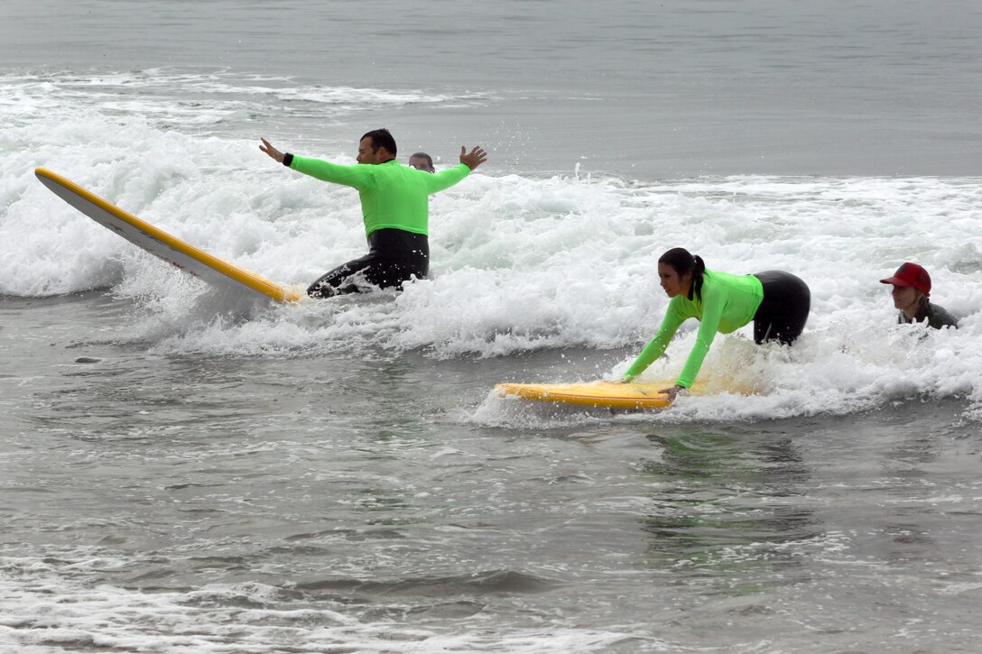 Jamie and Bri Roberts learn to stand on the surfboard during the Operation Amped surf clinic at San Onofre beach here Aug. 24. Billabong helped provide equipment and wetsuits for the veterans to use. Jamie is a sales job supervior and Bri is a office manager for Apollo Pavers.