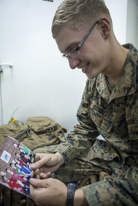 Lance Cpl. Gregg J. Schaefer, a landing support specialist with Combat Logistics Battalion 31, 31st Marine Expeditionary Unit, looks at a picture of himself with his 11 brothers and sisters here, Aug. 21.  With his siblings serving as the motivation to change his ways, Schaeffer transformed himself from troublemaker to role model by becoming a Marine. The 31st MEU is the Marine Corps’ force in readiness in the Asia-Pacific region and the only continuously forward deployed MEU. 