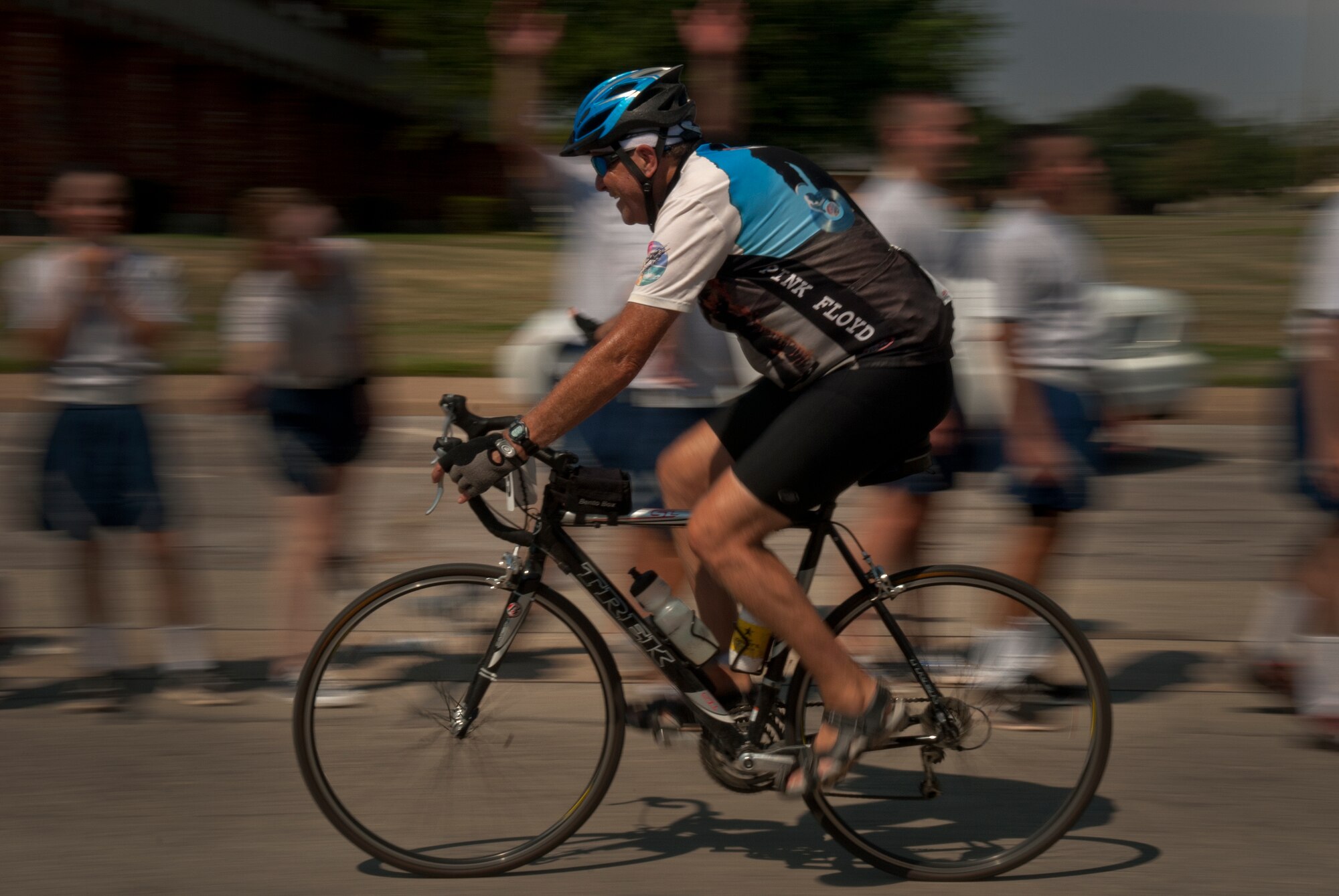A Hotter'N Hell Hundred rider greets Airmen in training at Sheppard Air Force Base, Texas, on his way out of the base Aug. 24, 2013. After "Airpower Alley" and a rest stop, bicycle riders rode through a gauntlet of hundreds of Airmen screaming and cheering them on to the finish line. The annual race is in its 32 year and celebrates to founding members of Texoma with a 100-mile race in 100-degree temperatures. (U.S. Air Force photo/Staff Sgt. Mike Meares)