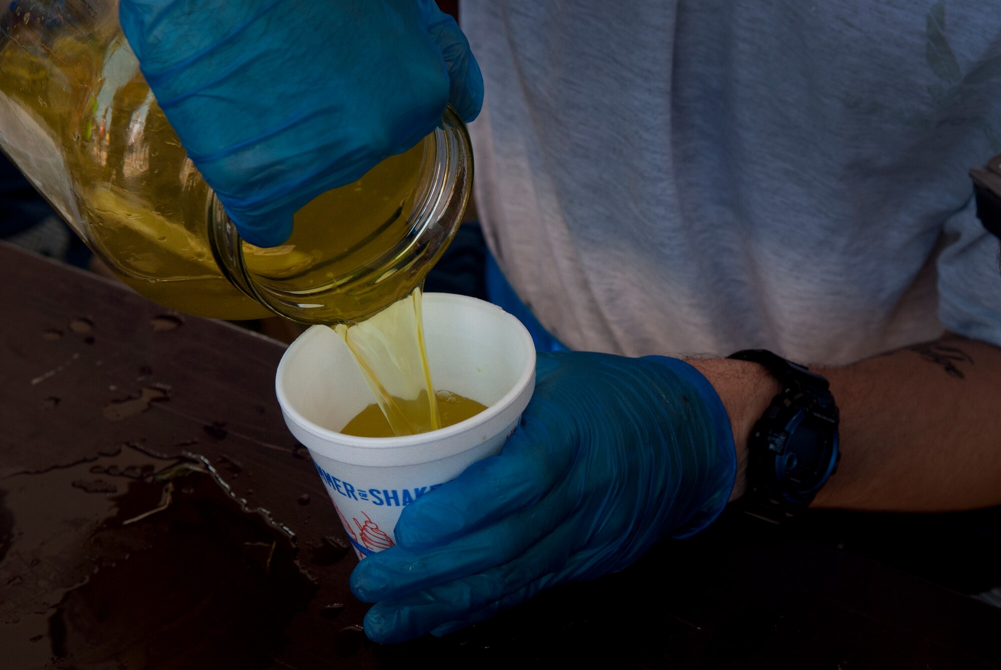An Airman pours fresh pickle juice into a cup for a Hotter'N Hell rider Aug. 24, 2013, at Sheppard Air Force Base, Texas. As part of the event, Sheppard volunteers also helped riders needing a break at the last rest stop before the finish line. Across all the rest stops, riders consumed more than 20,000 bananas, more than 9,000 oranges, more than 8,000 pickles, 2,800 gallons of PowerAde and 10,000 gallons of water. In all, more than 70,000 pounds of ice was also used. (U.S. Air Force photo/Staff Sgt. Mike Meares)