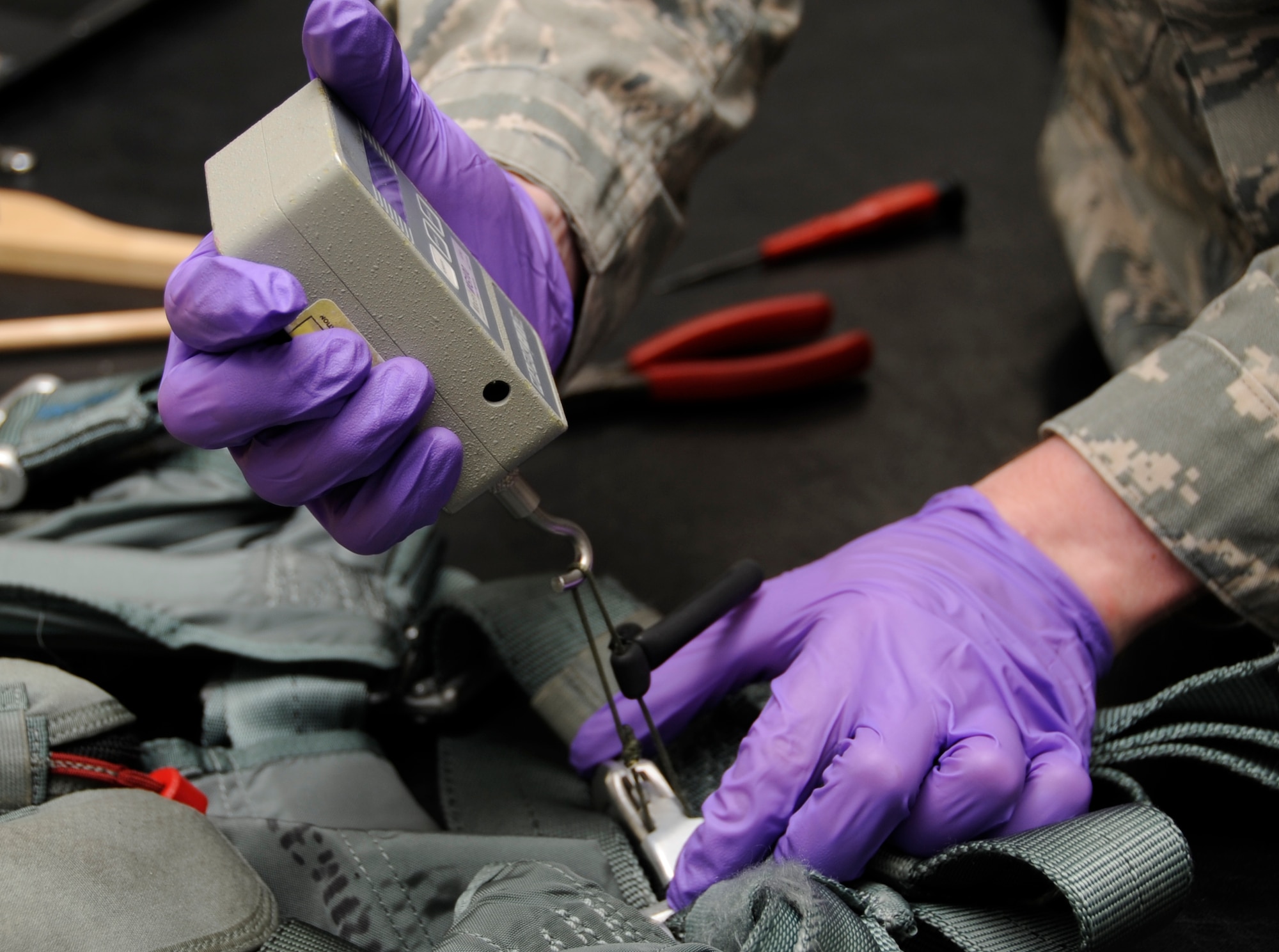 U.S. Air Force Senior Airman Jase Burnett, 35th Operations Support Squadron aircrew flight equipment technician, pull-tests an ejector strap to ensure it is safe for use at Misawa Air Base, Japan, Aug. 22, 2013. A pilot’s harness must be inspected every 30 days to ensure it is serviceable and will not put a pilot’s life in danger. (U.S. Air Force photo by Airman 1st Class Kaleb Snay)
