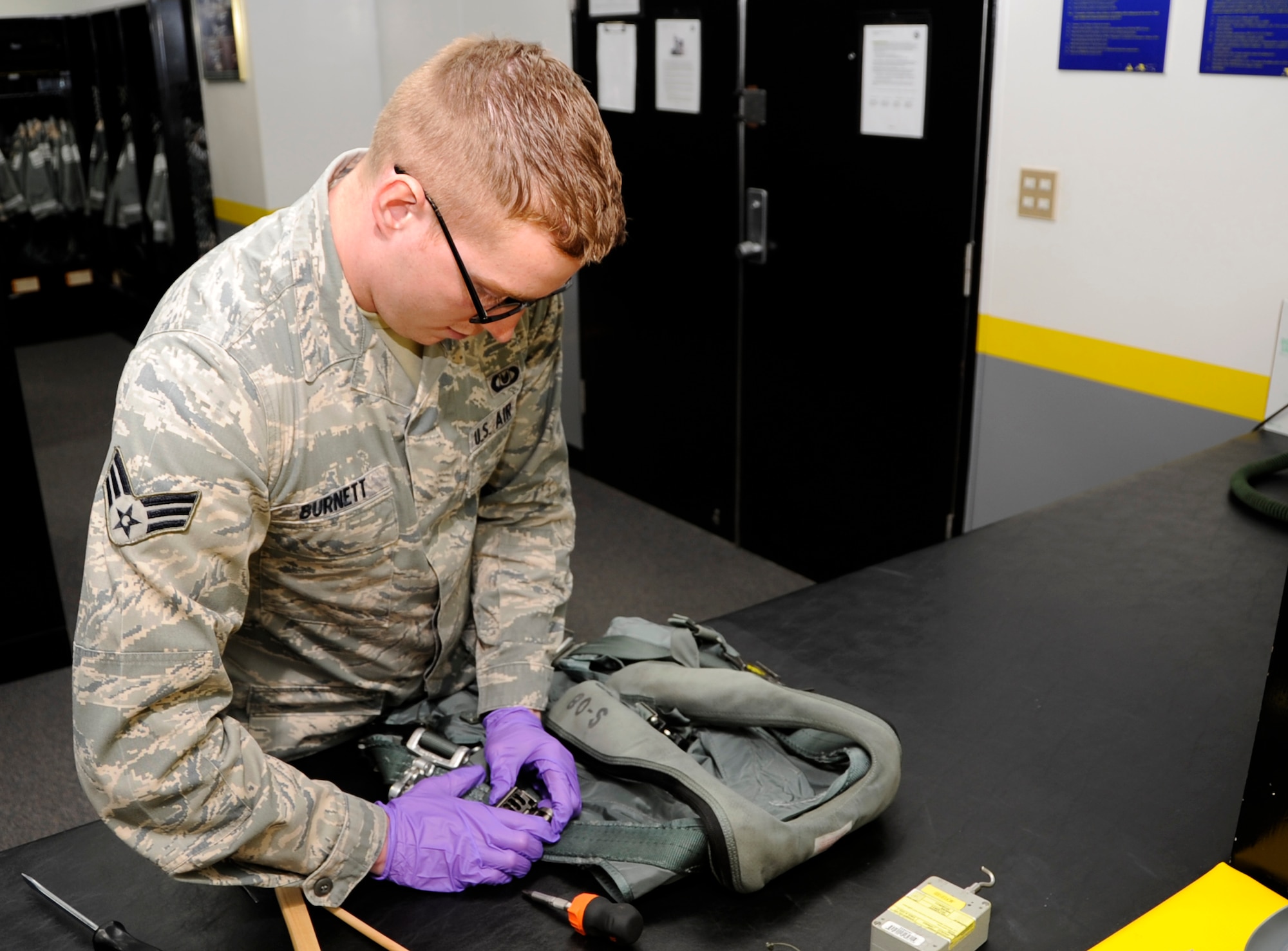 U.S. Air Force Senior Airman Jase Burnett, 35th Operations Support Squadron aircrew flight equipment technician, checks for cracks in an ejector strap spring at Misawa Air Base, Japan, Aug. 22, 2013. If cracks or other discrepancies exist on the harness, it could potentially injure pilots if they need to eject from an F-16 Fighting Falcon. (U.S. Air Force photo by Airman 1st Class Kaleb Snay)