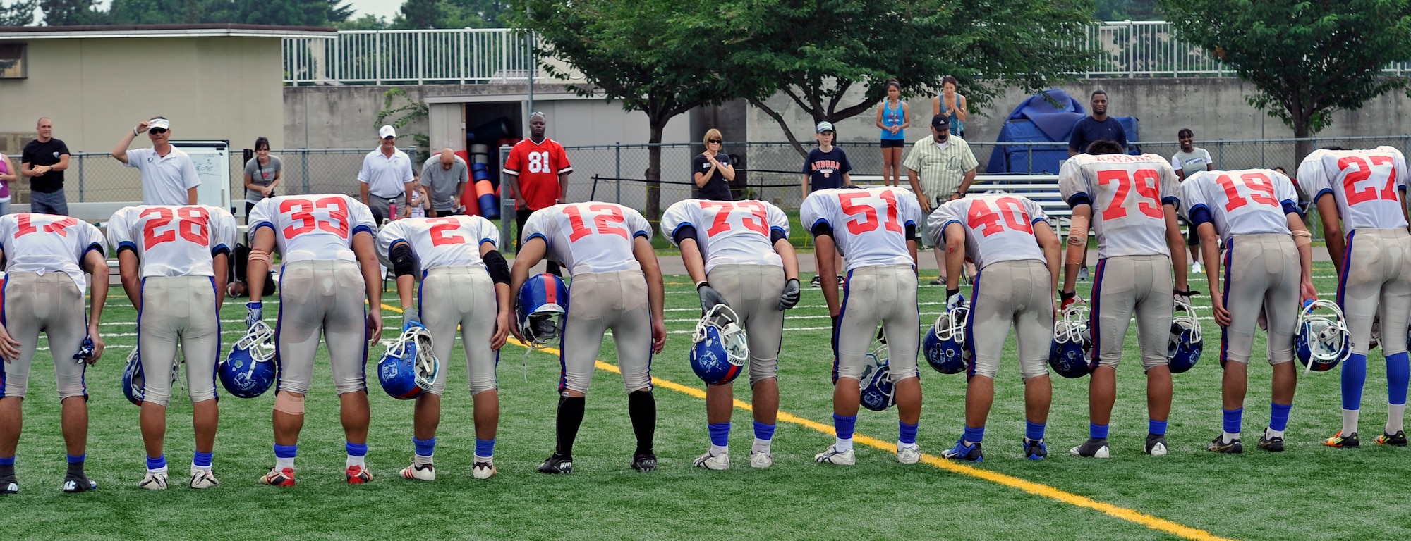 Players from the Tohoku Gakuin University football team bow in thanks to the family and fans of the Edgren High School football team after their scrimmage at Misawa Air Base, Japan, Aug. 18, 2013. Over the weekend, players from the university stayed on base and participated in a football camp with the Edgren High School football team. (U.S. Air Force photo by Airman 1st Class Zachary Kee)