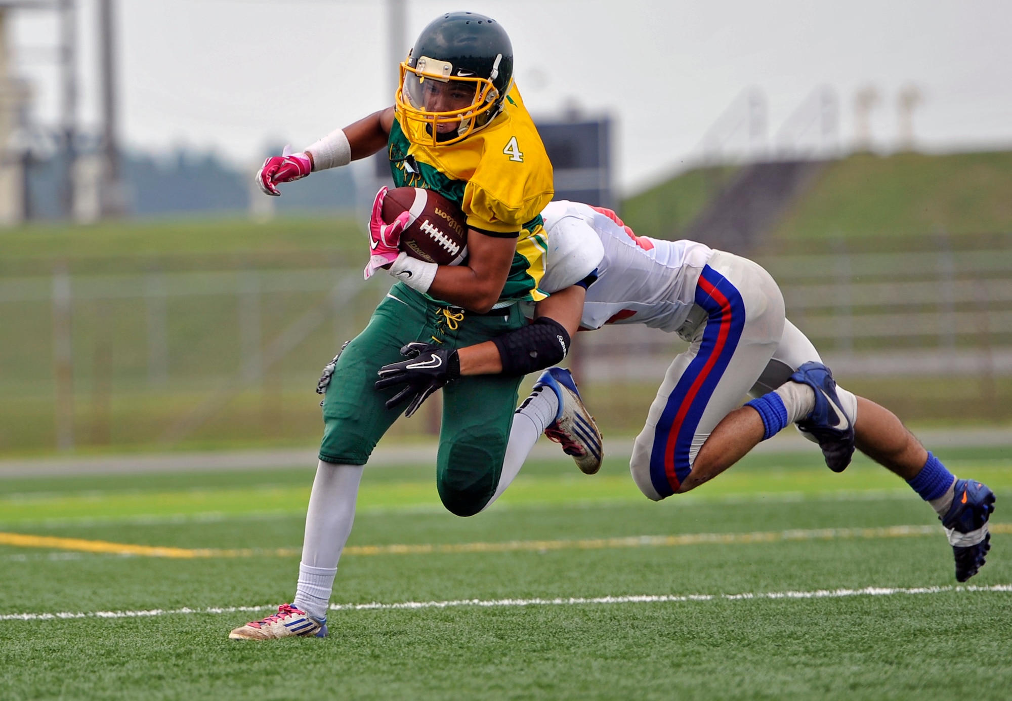 A defensive back on the Tohoku Gakuin University football team wraps up Tyrone Balcaslo, Edgren High School senior tailback, during a scrimmage at Misawa Air Base, Japan, Aug. 18, 2013. Edgren kicked off their season against Yokota Aug. 23, 2013 and recently used a bilateral football camp with players from TGU to help prepare for their season. (U.S. Air Force photo by Airman 1st Class Zachary Kee)