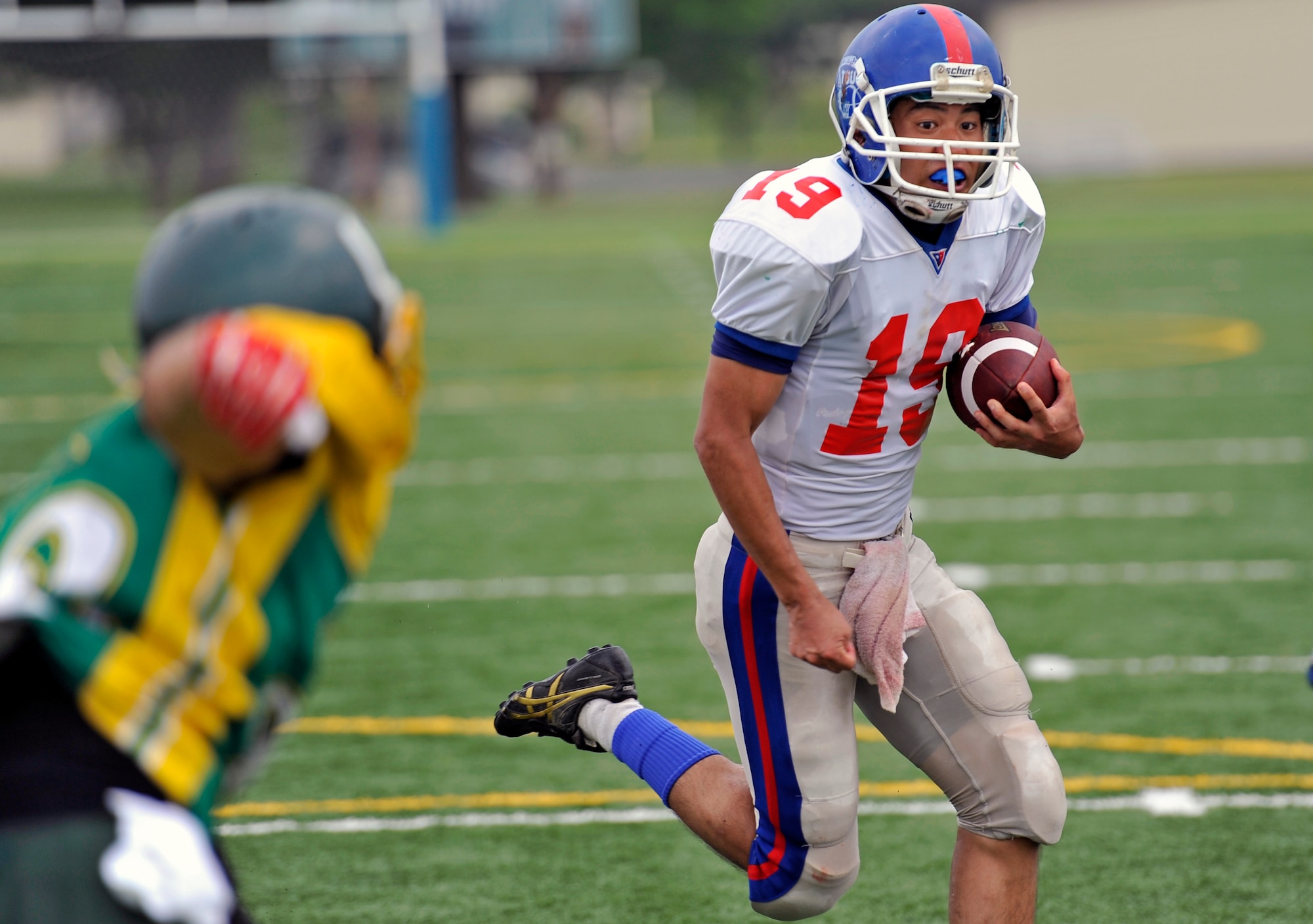 The quarterback of the Tohoku Gakuin University football team scrambles away from pressure during a scrimmage at Misawa Air Base, Japan, Aug. 18, 2013. Players from TGU spent the weekend with players from Edgren High School and participated in a bilateral football camp that prepared both teams for their upcoming seasons. (U.S. Air Force photo by Airman 1st Class Zachary Kee)