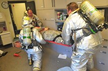 Airmen from the 115th Fighter Wing participated in a unexpected exercise designed to test mission readiness on base Aug. 23, 2013.  An unauthorized front-gate entry and a simulated explosion started the exercise leading to a 'fire' in Building 411.   The explosive ordinance disposal team here added realism by filling that building up with smoke, giving the rescue teams a challenge when removing the victims.  (Air National Guard photo by Staff Sgt. Ryan Roth)