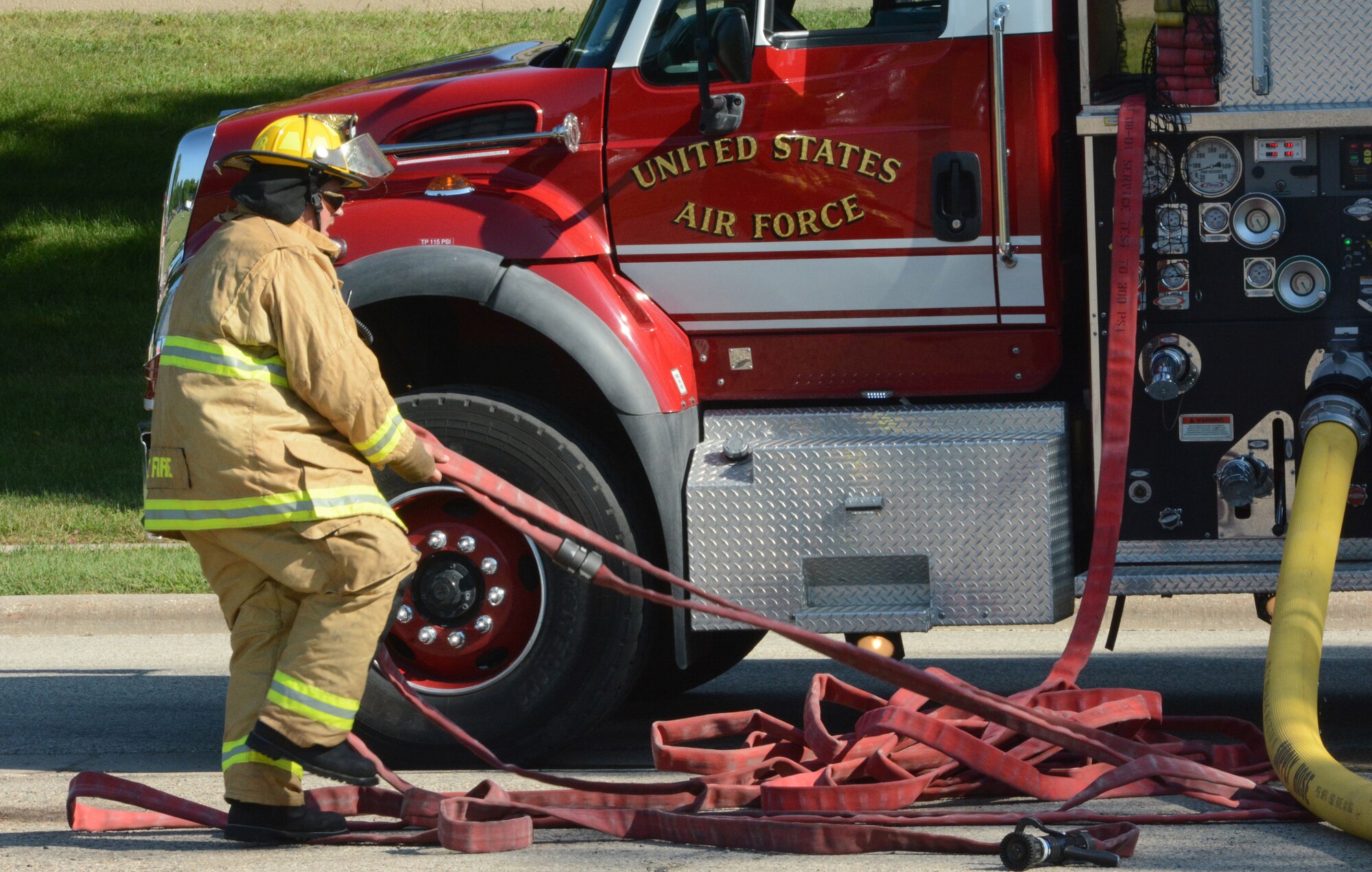 A firefighter from the 115th Civil Engineer Squadron prepares a water hose for use during a bomb exercise at Truax Field, Madison, Wis., Aug. 23, 2013. The Hazmat Pharmacy Environmental building was smoking following a simulated bomb explosion, so firefighters rushed to the scene to rescue victims inside. The exercise was part of a new Air Force Inspection System initiative. (Air National Guard photo by Senior Airman Andrea F. Liechti)