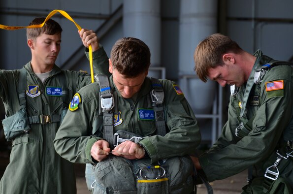 Members of the 736th Security Forces Squadron assist each other in gearing up Aug. 21, 2013, before static line jump training on the Andersen Air Force Base, Guam. The Air Force static line capability falls under the personnel parachute program. Jumpers are first qualified during a three-week long basic airborne course at Ft. Benning, Ga., and then continue to work on their jumping proficiency and qualifications after they return here. 