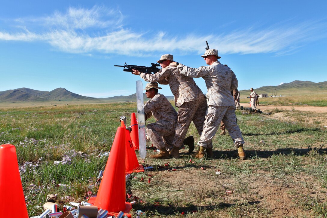 (From left) Sgt. Patrick Garza, Gunnery Sgt. Mark Massalski, and Staff Sgt. Alan Stowers, all non-lethal weapons instructors with 3rd Law Enforcement Battalion, III Marine Expeditionary Force, demonstrate a common team formation while conducting non-lethal weapons drills at Five Hills Training Area, Mongolia, Aug. 23. Prior to sending non-lethal ammunition downrange, personnel with the Mongolian Armed Forces and General Police received classroom instruction, a safety brief and conducted dry runs with various non-lethal weapon systems. The training took place as part of the Non-Lethal Weapons Executive Seminar (NOLES) field training exercise, hosted annually in the Pacific region and led this year by U.S. Marines with 3rd LE Battalion out of Okinawa, Japan. Mongolia, a regular participant, is hosting NOLES for the third time in 12 years. Garza is from Dallas, Massalski is from Townsend, Mass., and Stowers is from Garber, Okla.