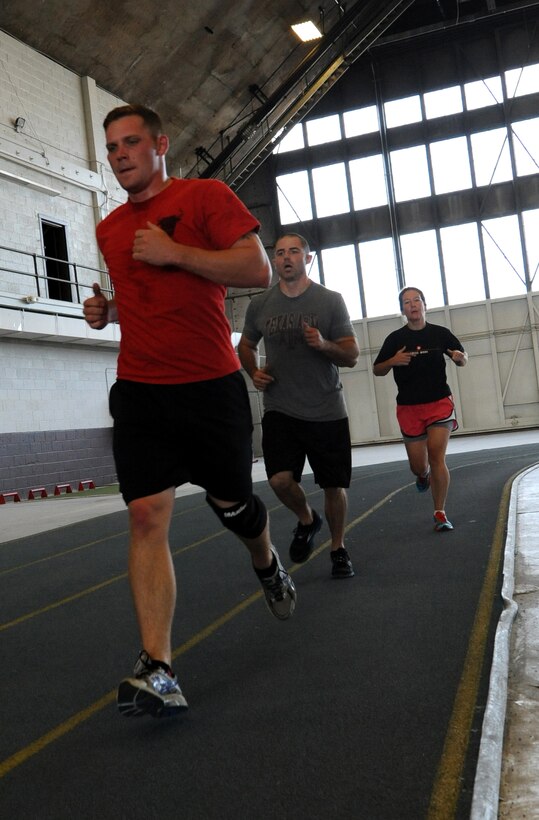 Runners cross the finish line during the Mash Fitness competition in the Pride Hangar at Ellsworth Air Force Base, S.D., Aug. 23, 2013. Five teams of four or more competitors each competed in nine different events that ranged from strength and fitness activities to running and endurance. (U.S. Air Force photo by Airman 1st Class Hrair H. Palyan/Released)