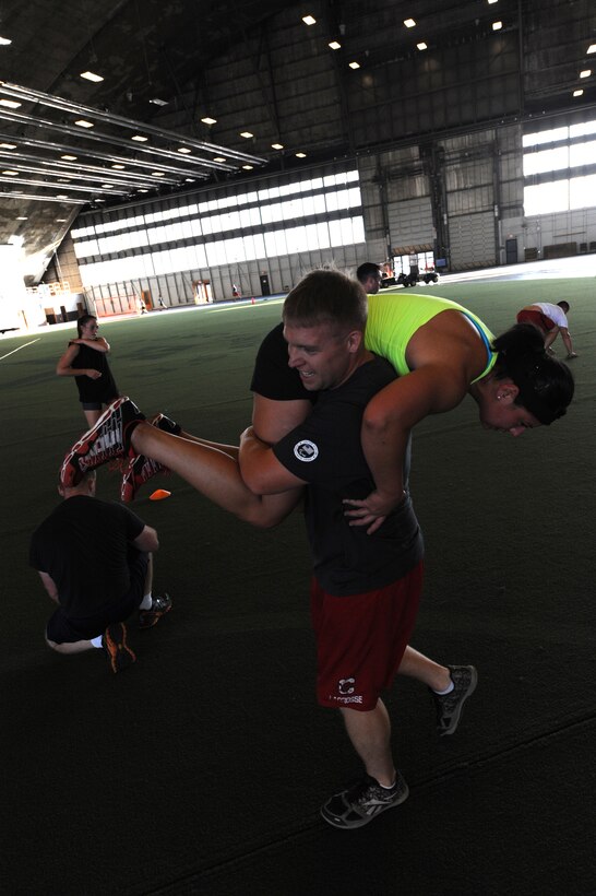 Competitors participate in a rescue carry event during the Mash Fitness competition in the Pride Hangar at Ellsworth Air Force Base, S.D., Aug. 23, 2013. More than 20 Airmen, family members and civilians put their physical abilities to the test to see which team would rise to the challenge and complete the tasks in the shortest amount of time. (U.S. Air Force photo by Airman 1st Class Hrair H. Palyan/Released)