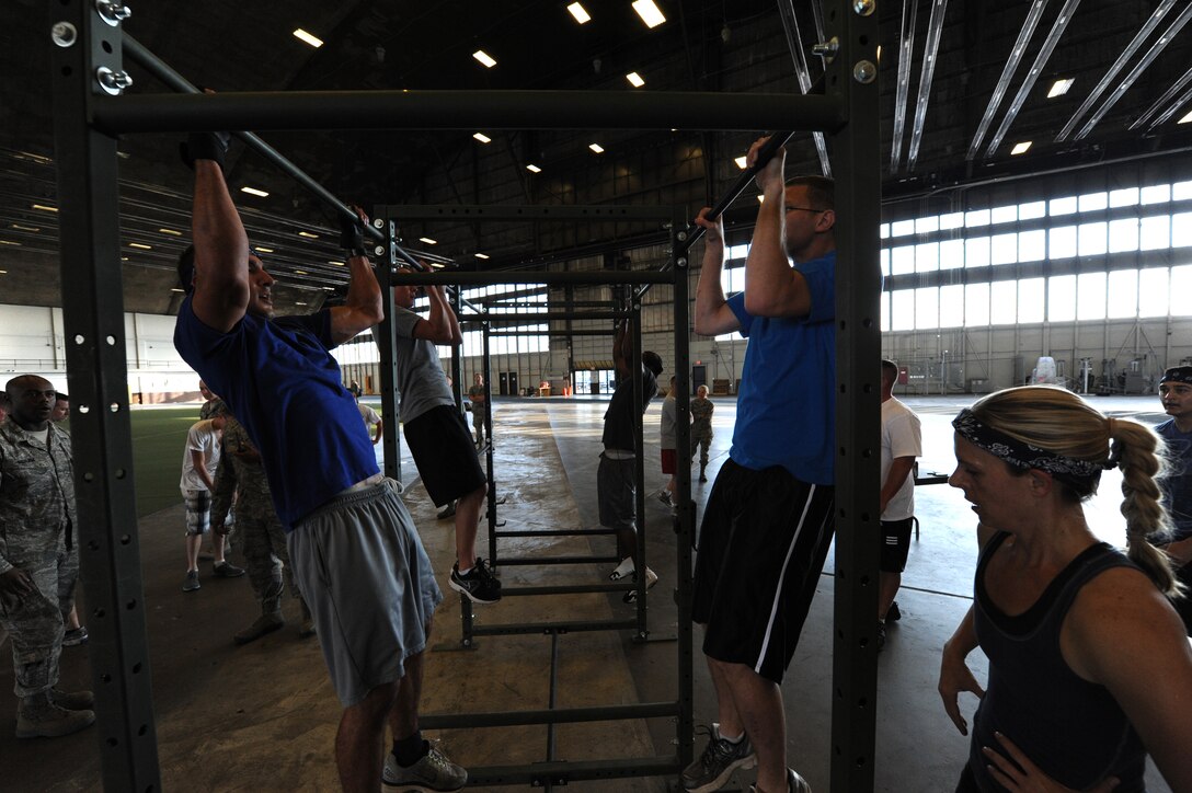 Airmen perform pull-ups during the Mash Fitness competition in the Pride Hangar at Ellsworth Air Force Base, S.D., Aug. 23, 2013. Each team was required to designate a team member with the responsibility of timing each event. In the end, judges collected completion times from each team and determined the winner of the event. (U.S. Air Force photo by Airman 1st Class Hrair H. Palyan/Released)