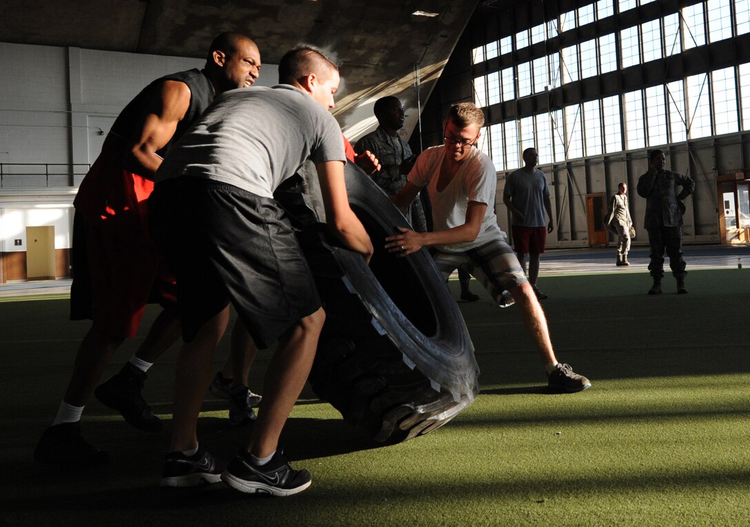 Airmen participate in a 50-yard tire flip event during the Mash Fitness competition in the Pride Hangar at Ellsworth Air Force Base, S.D., Aug. 23, 2013. During the event, five teams comprised of Airmen from different units across the base competed in more than 9 events to determine which team could complete the events in the shortest amount of time. (U.S. Air Force photo by Airman 1st Class Hrair H. Palyan/Released)