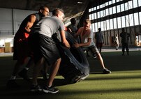 Airmen participate in a 50-yard tire flip event during the Mash Fitness competition in the Pride Hangar at Ellsworth Air Force Base, S.D., Aug. 23, 2013. During the event, five teams comprised of Airmen from different units across the base competed in more than 9 events to determine which team could complete the events in the shortest amount of time. (U.S. Air Force photo by Airman 1st Class Hrair H. Palyan/Released)