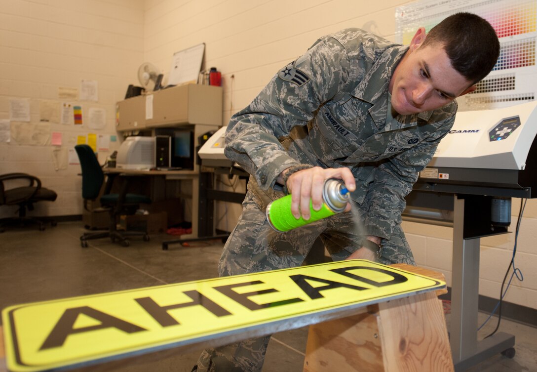 Senior Airman Benjamin Amirault, 28th Civil Engineer Squadron structures technician, sprays an ultra violet protective coating on a finished traffic sign at Ellsworth Air Force Base, S.D., Aug. 15, 2013. In the final step of the sign-making process, the UV coating provides a layer of protection from the elements increasing the life of the signs and prevent fading from the sun. (U.S. Air Force photo by Airman 1st Class Alystria Maurer/Released)