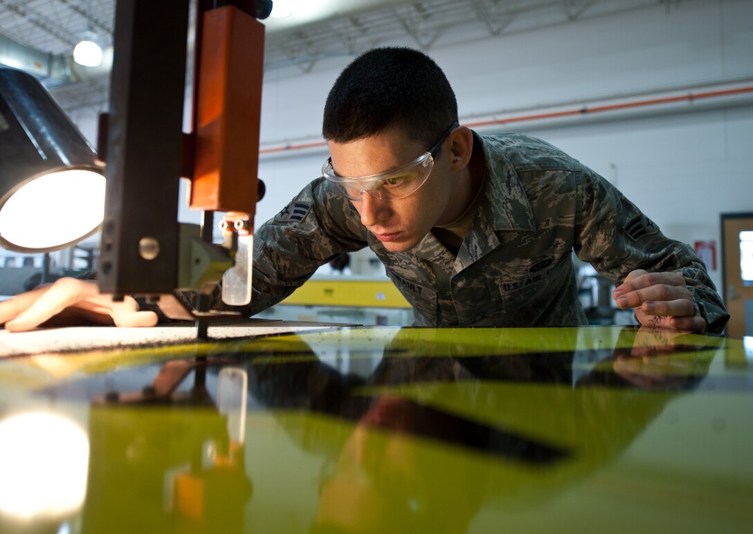Senior Airman Benjamin Amirault, 28th Civil Engineer Squadron structures technician, uses a bandsaw to remove extra poly-metal from a crosswalk sign at Ellsworth Air Force Base, S.D., Aug. 15, 2013. The CES sign shop creates a wide variety of signs including traffic, building, street, safety, and special event signs. (U.S. Air Force photo by Airman 1st Class Alystria Maurer/Released)