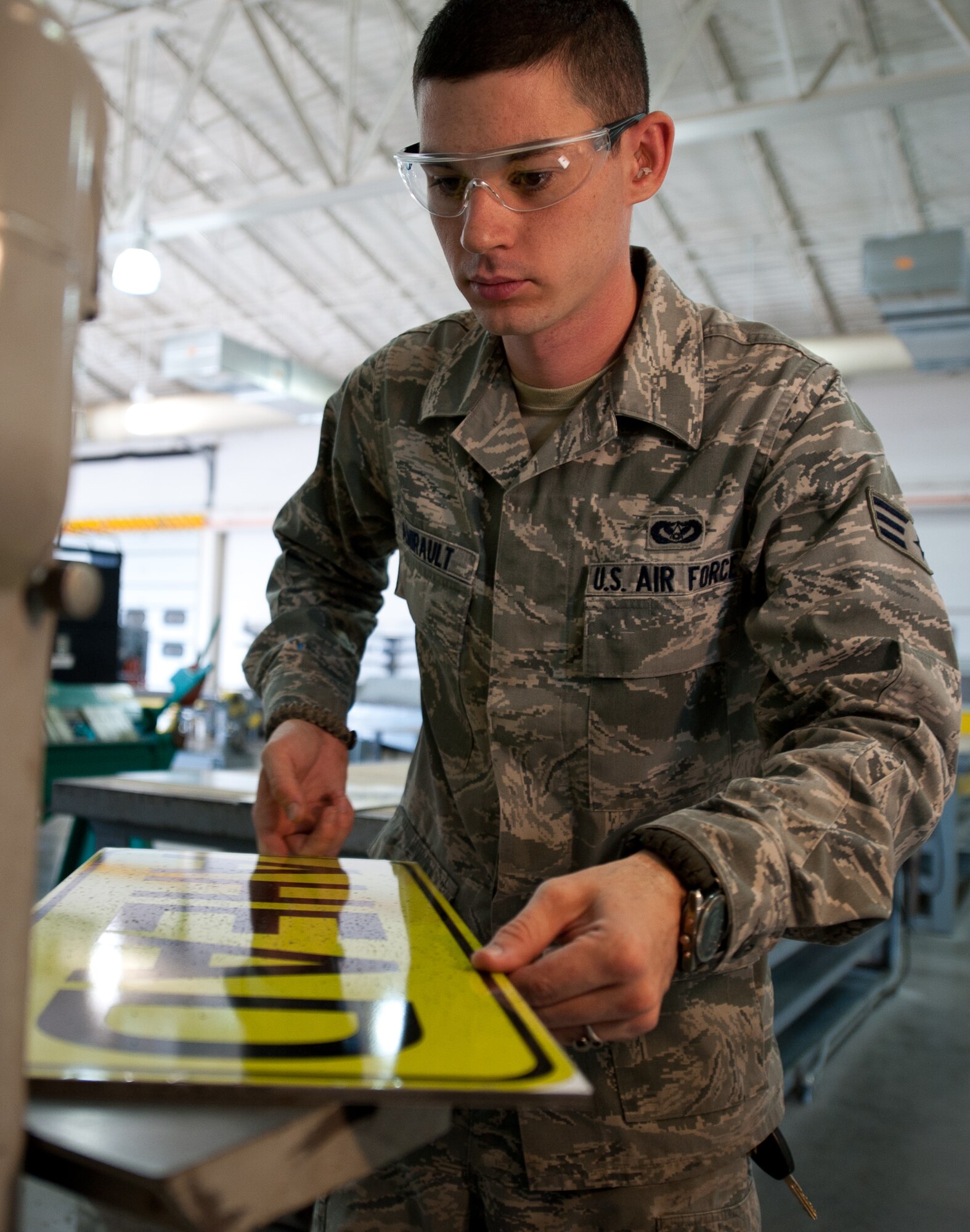 Senior Airman Benjamin Amirault, 28th Civil Engineer Squadron structures technician, uses a belt sander to round the corners of a traffic sign at Ellsworth Air Force Base, S.D., Aug. 15, 2013. Technicians flatten the corners of each sign to provide a finished product free of sharp edges. (U.S. Air Force photo by Airman 1st Class Alystria Maurer/Released)