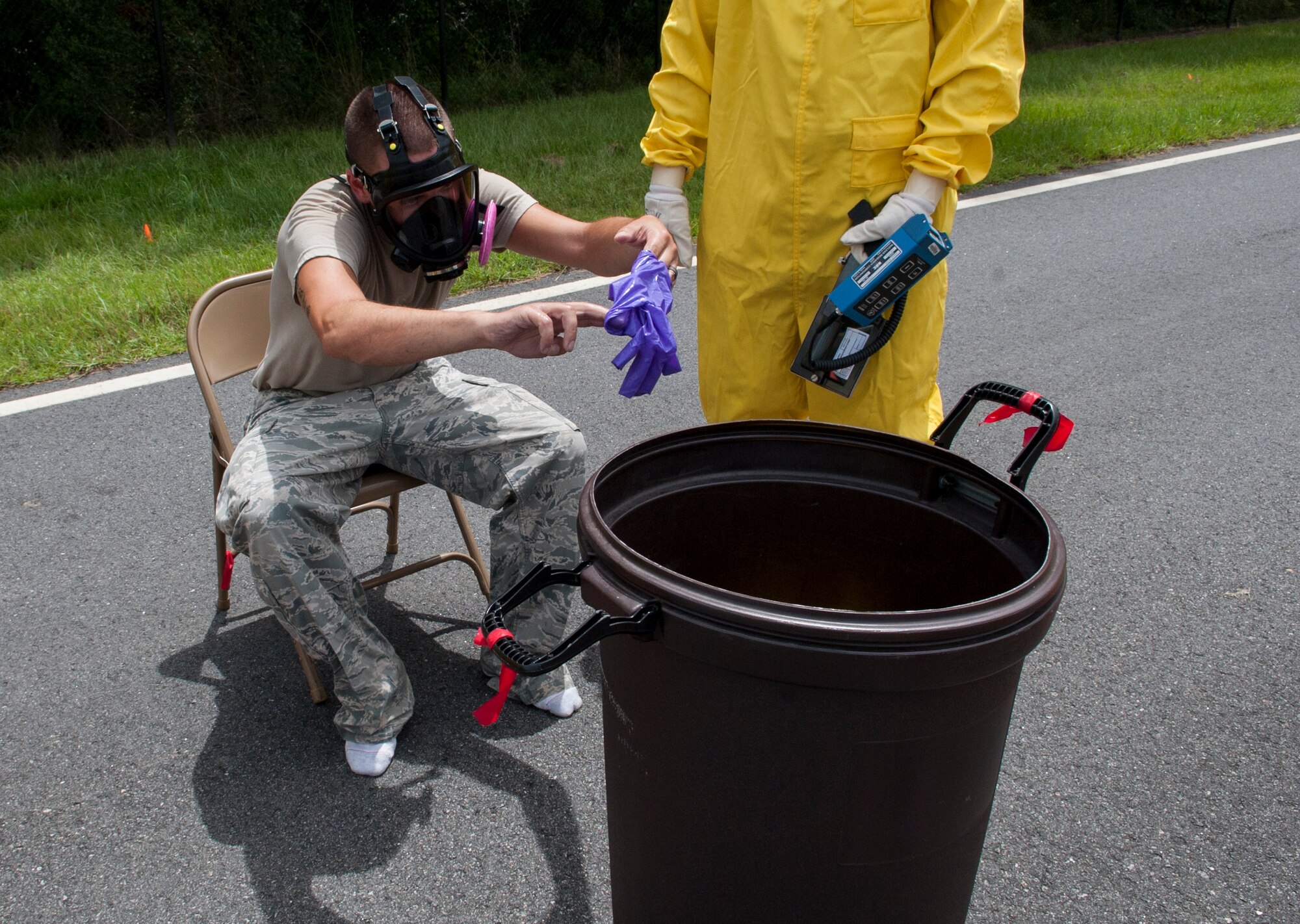 U. S. Air Force Senior Airman Justin Roberts, 23d Medical Group bioenvironmental engineering technician, carefully disposes of his gloves during a nuclear weapons incident exercise at Moody Air Force Base, Ga., Aug. 16, 2013. Roberts went through a six-step process to remove his radiation suit. (U.S. Air Force photo by Airman 1st Class Sandra Marrero/released)
