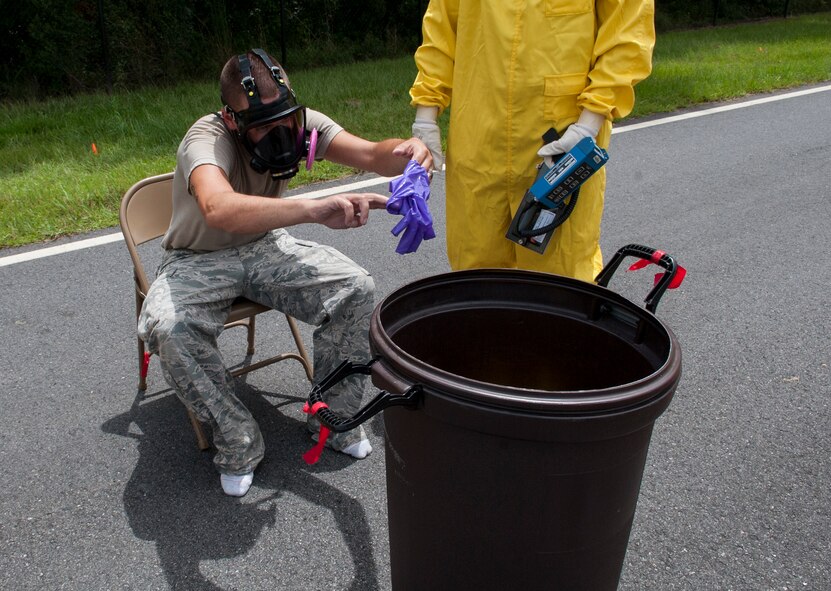 U. S. Air Force Senior Airman Justin Roberts, 23d Medical Group bioenvironmental engineering technician, carefully disposes of his gloves during a nuclear weapons incident exercise at Moody Air Force Base, Ga., Aug. 16, 2013. Roberts went through a six-step process to remove his radiation suit. (U.S. Air Force photo by Airman 1st Class Sandra Marrero/released)
