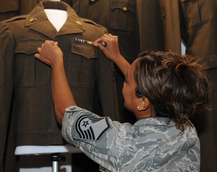 Master Sgt. Editha Decuir, 307th Dental Squadron and museum volunteer, adjusts the ribbons on a uniform display at the Global Power Museum on Barksdale Air Force Base, La., Aug. 26, 2013. Decuir adjusted the ribbons to make the uniform look sharp for visitors. The museum currently has an exhibit which displays uniforms and artifacts from the World War II era. (U.S. Air Force photo/Senior Airman Benjamin Gonsier)